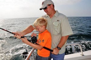 dad helping son reel in a fish
